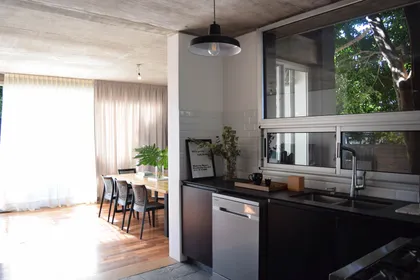 Cocina moderna negra con mesada de madera y ventanal al jardin — proyecto Casa Punta Chica , por Estudio Simbiosis, en Punta Chica