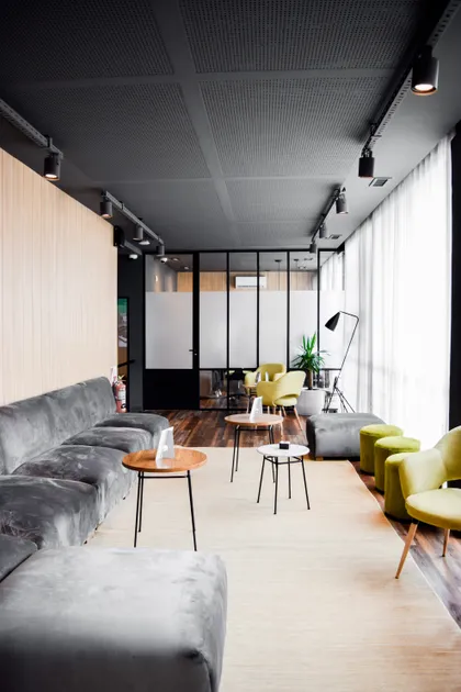 Living contemporáneo con sofás grises, sillones verdes y techo negro industrial — proyecto Espacio BaPro, por Estudio Simbiosis