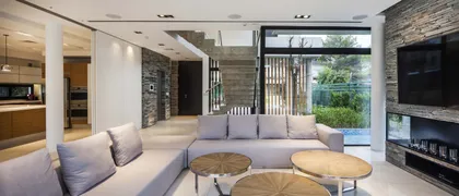 Living moderno con pared de piedra y ventanales al jardín — proyecto Simpleza moderna, por Apaarquitectura