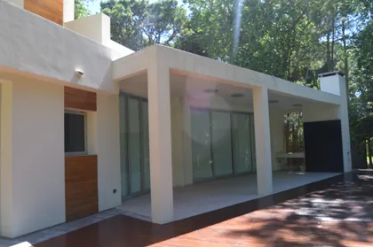 Fachada moderna con patio cubierto y detalles en madera — proyecto CARILO - Boyero, por LADAGA-RUARTE-Pinamar, en Cariló