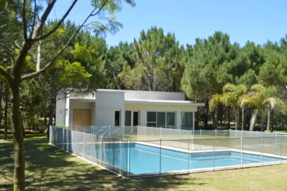 Casa moderna con piscina rodeada de árboles — proyecto LA HERRADURA - Boulevard I, por LADAGA-RUARTE-Pinamar, en Pinamar