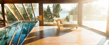 Living moderno con piscina de vidrio y vistas al bosque — proyecto Casa Villa La Angostura, por Sidoni & Asociados, en Villa La Angostura