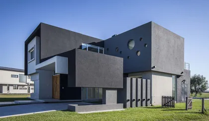 fachada moderna con volúmenes contrastantes y grandes paneles grises — proyecto AM House, por A+R Arquitectos