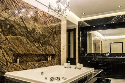Baño de lujo con pared de mármol, bañera exenta y araña de cristal — proyecto CF House, por A+R Arquitectos
