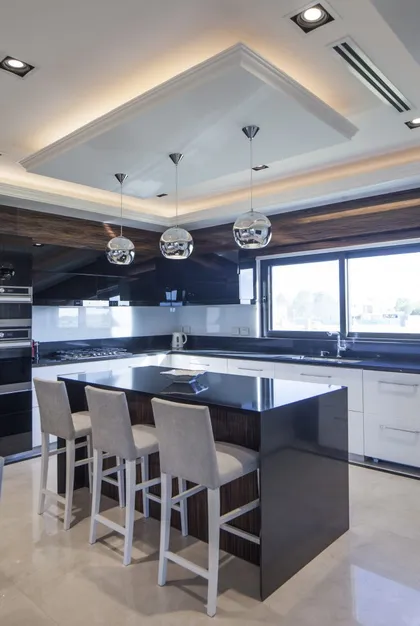 Cocina moderna con isla central, luces integradas y ventanas amplias — proyecto SR House, por A+R Arquitectos