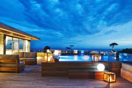 terraza exterior de hotel con piscina infinita y muebles modernos de noche — proyecto Dos Mares, por Pacifica Arquitectura
