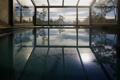 piscina interior con techo vidriado y vista a la montaña — proyecto Casa Muelle de Piedra, por Sidoni & Asociados, en Villa La Angostura