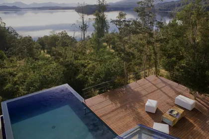 Piscina infinita con deck de madera y vista al bosque — proyecto Casa Muelle de Piedra, por Sidoni & Asociados, en Villa La Angostura