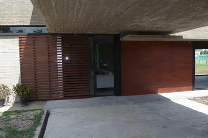 Fachada contemporánea con pérgola de madera y entrada vidriada — proyecto Casa Canning, por Luciano Kruk, en Canning