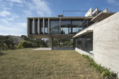 Casa moderna con fachada hormigón y jardin amplio al frente — proyecto Casa Cariló, por Luciano Kruk, en Cariló