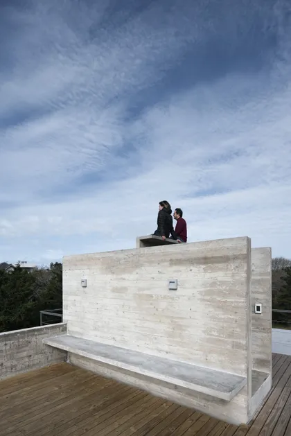 Dos personas sentadas en estructura hormigón sobre terraza con deck — proyecto Casa Cariló, por Luciano Kruk, en Cariló