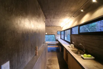 Cocina moderna alargada con mesada de madera y ventanales panorámicos — proyecto Casa de Hormigón, por Luciano Kruk
