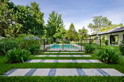 Piscina moderna rodeada de vegetación exuberante con pérgola y deck — proyecto Casa BA, por Estudio Dado, en Pilar