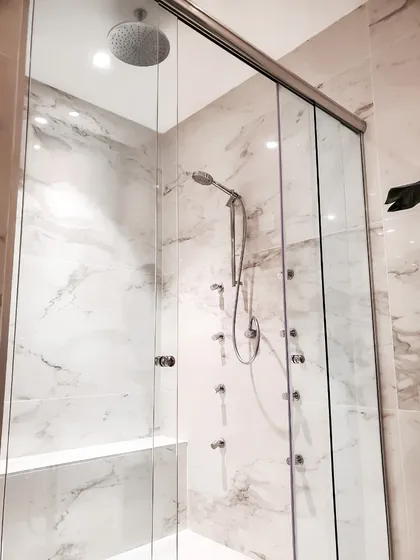 Baño moderno con paredes y ducha de mármol, vidrio y estante blanco — proyecto EL GOLF, NORDELTA , por Greschek Obras , en Nordelta