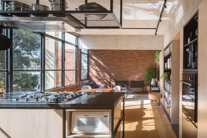 Cocina moderna con isla, ladrillo visto y gran ventanal con luz natural — proyecto Apartamento SQN 410, por Coda Arquitetos