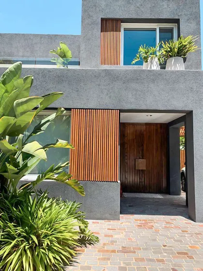 Fachada moderna de hormigón con vegetación prominente — proyecto LOS SAUCES, NORDELTA , por Greschek Obras , en Nordelta