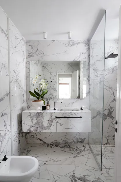 Baño moderno revestido en mármol, con bacha integrada y grifería negra — proyecto Alvear | Redefining luxury, por Ren Studio, en Recoleta