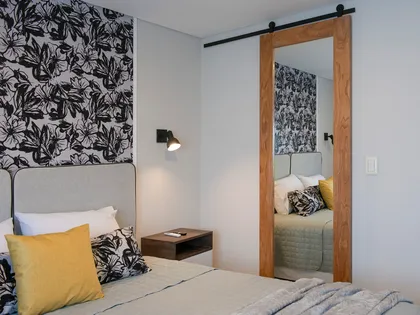 dormitorio moderno con papel mural floral y puerta corrediza de espejo — proyecto Alto Panorama, por Interiores a la carta, en Córdoba