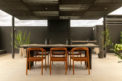 Comedor exterior con pérgola de madera y deck de cemento — proyecto Proyecto Cabello, por Alejandra Nusenovich, en Buenos Aires