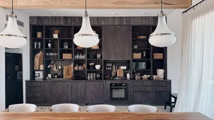 Cocina moderna de madera oscura con luces colgantes grandes — proyecto El Refugio, por Grupo Pauta Arquitectura, en Pinamar