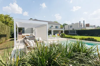 Pileta moderna con pérgola, sala de estar exterior y vegetación exuberante — proyecto TOLDER - PERGOLAS, por Argentina en Obra 2024, en Rincón de Milberg