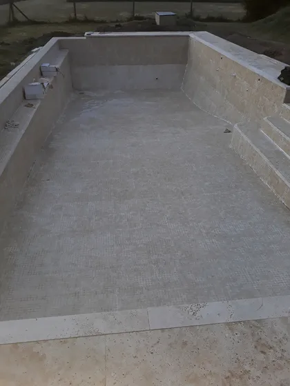 Pileta rectangular en construcción con piso de microcemento gris — proyecto piscina en ele, por Piscinas omar, en Pilar
