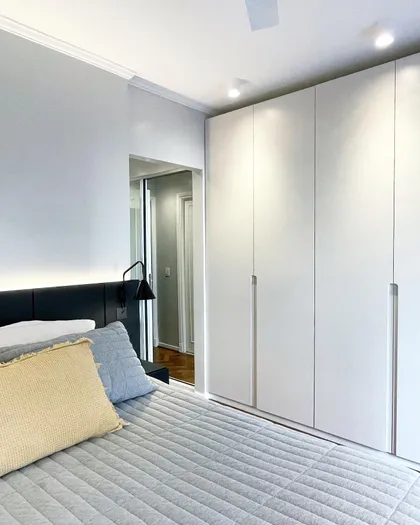 Dormitorio moderno con placard blanco integrado y luminaria negra — proyecto Paraná, por JT ARQUITECTURA, en Buenos Aires