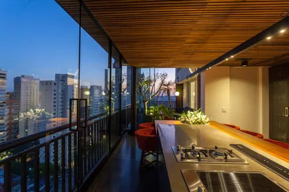 Balcón moderno con vista urbana y cocina integrada — proyecto TRIPLEX MARIO FERRAZ, por DB ARQUITETOS