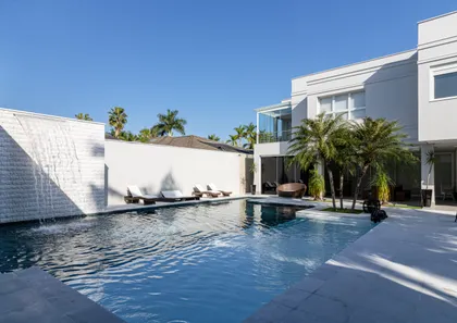 Amplio patio moderno con piscina, cascada y palmeras — proyecto Mansão de Gabigol, por Carlos Pardal, en Guarujá