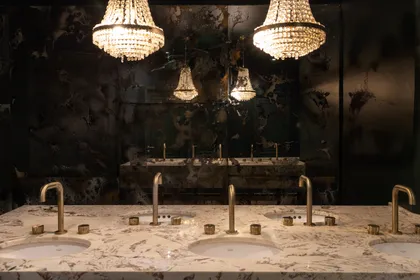 Baño de lujo con candelabros de cristal y mármol — proyecto PRESIDENTE BAR HIPODROMO, por AB ARQUITECTURA, en San Isidro