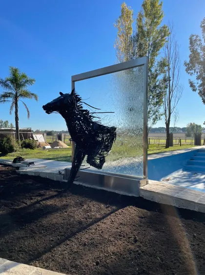Escultura de caballo en piscina con cascada de vidrio — proyecto Fuente de Agua con figura Caballo, por FUENTES Y MUROS .COM.AR, en Canning