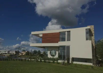 Fachada moderna con volúmenes geométricos, madera y piedra — proyecto Casa Cinta, por Barrionuevo Arquitects, en B2814 Los Cardales