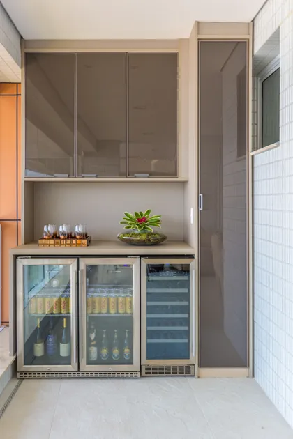 Terraza balcón moderna con bar integrado y heladeras — proyecto Apartamento Riviera, por Patrícia Hagobian Arquitetura e Interiores