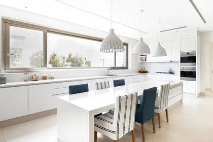 Cocina moderna abierta con isla grande, ventanales y sillas a rayas — proyecto Casa DF, por Estudio Junor, en Tigre