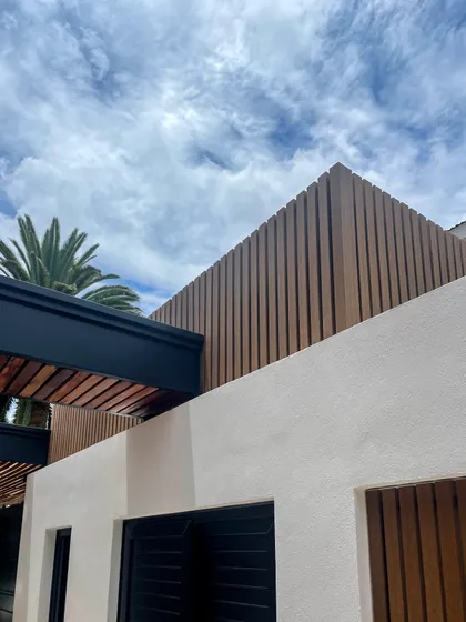 Fachada moderna con revestimiento de listones de madera y paredes texturizadas blancas — proyecto Obra La Posta, por Arq. Lourdes Yarade Saravia, en Pilar