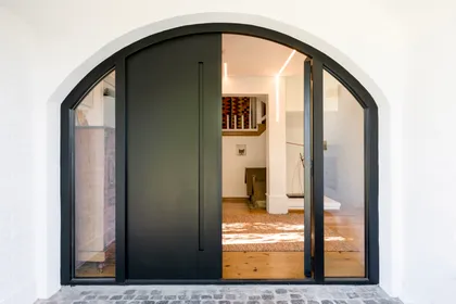 Fachada moderna con puerta pivotante negra y arco — proyecto Boating Club, por SRMD Arquitectura, en Boating Club