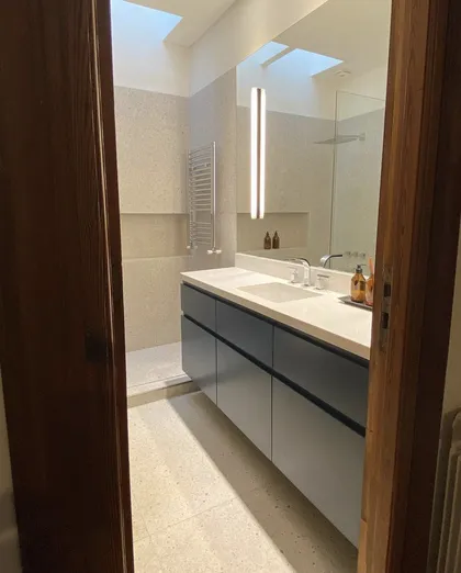 Baño moderno con vanitory flotante gris, bacha integrada y claraboya — proyecto Baños Belgrano, por Cudini Estudio, en Belgrano