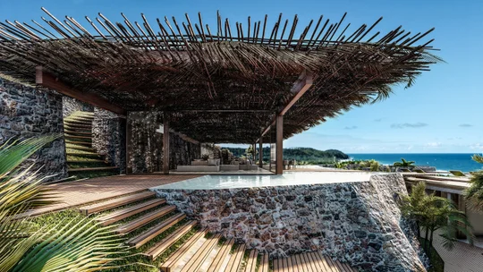 Terraza con pergola de ramas, deck de madera y vista al mar — proyecto Bangalo Txai, por Tetro Arquitetura