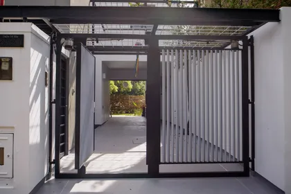 puerta de entrada moderna con paneles acanalados y rejilla — proyecto CASA GONNET, por LEONE LORAY ARQUITECTOS, en Gonnet