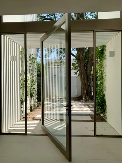 puerta pivotante de vidrio y madera exterior moderna — proyecto CASA BECCAR, por Estudio Xime Fontan Balestra, en Béccar