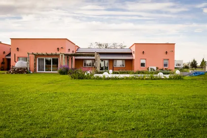 Casa moderna color terracota con amplio césped y patio — proyecto La casa del árbol, por Estudio Fernandez Long & asoc., en Canning