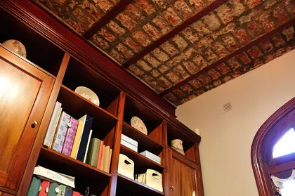 Techo artesonado de ladrillo y estanterías de madera oscura — proyecto Casa en Belgrano R, por Rioja Arquitectura, en Belgrano R