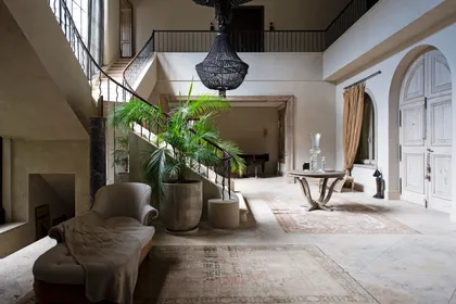 Hall de doble altura con escalera, plantas y luz natural abundante — proyecto Casa Toscana , por Estudio Du