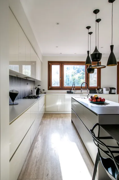 Cocina moderna minimalista blanca con isla central y grandes ventanales — proyecto CasaLA, por Ricardo Pereyra Iraola