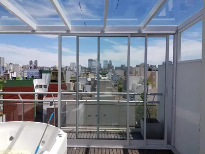 terraza moderna con bañera exenta y vista urbana — proyecto Cerramiento aluminio Modena en terraza, por Cristalcenter, en Palermo