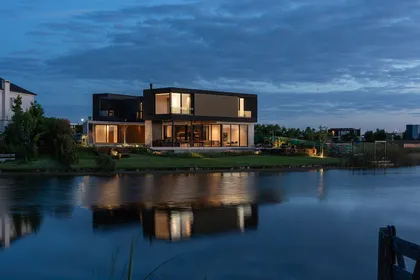 fachada moderna junto al agua con piscina y deck — proyecto CASA MUELLES, por GMARQ, en Escobar