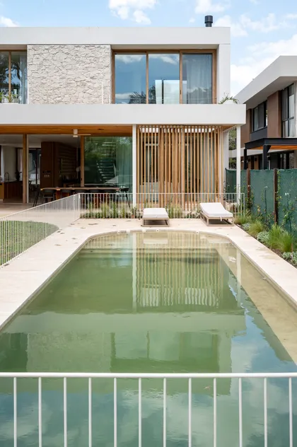 Fachada moderna con piscina reflectante y sillas de exterior — proyecto CASA CT 1, por Casa Cunia, en Buenos Aires