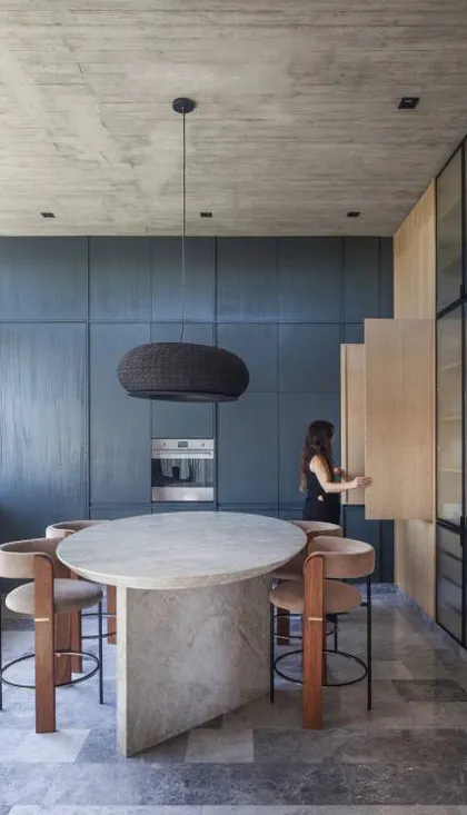 Cocina moderna con isla de piedra y paredes azules texturizadas — proyecto Casa Órbita, por Estudio PK, en Nordelta