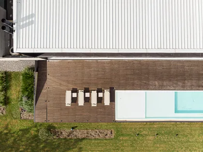 Pileta moderna con deck de madera y reposeras blancas — proyecto PG.A, por Casa Cunia, en Buenos Aires