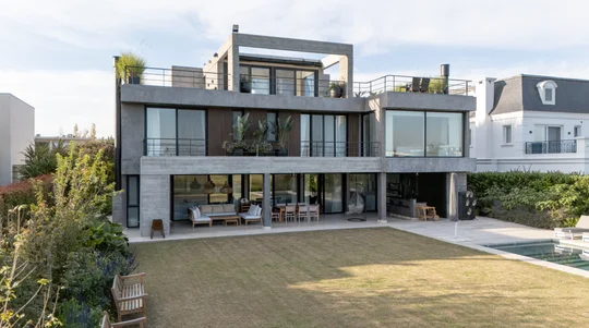 Fachada moderna con amplios ventanales y deck de madera — proyecto Obra Golf Nordelta, por lifecycle, en Tigre